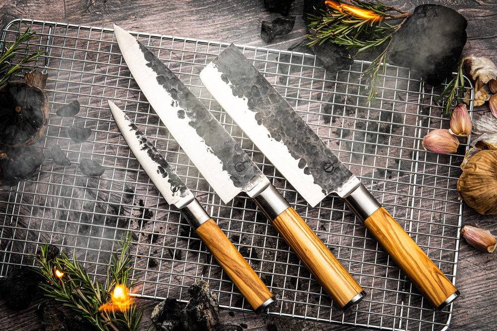 Forged Olive messen met olijfhouten heft op een grillrooster bij het vuur